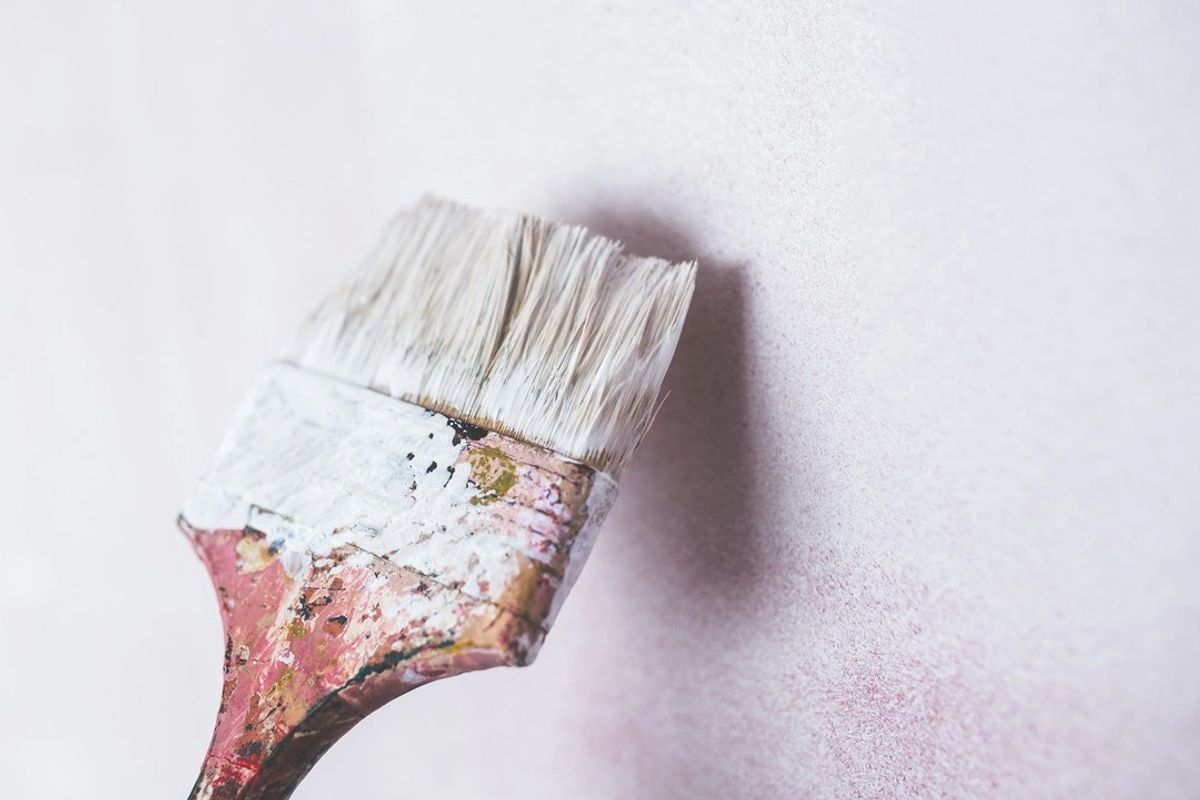 A loaded paintbrush against a freshly painted wall